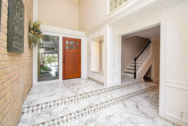 201 Vanderpool Ln Unit 27, Houston, TX 77024 - foyer entrance featuring light marble finish flooring, stairway, a towering ceiling, and brick wall