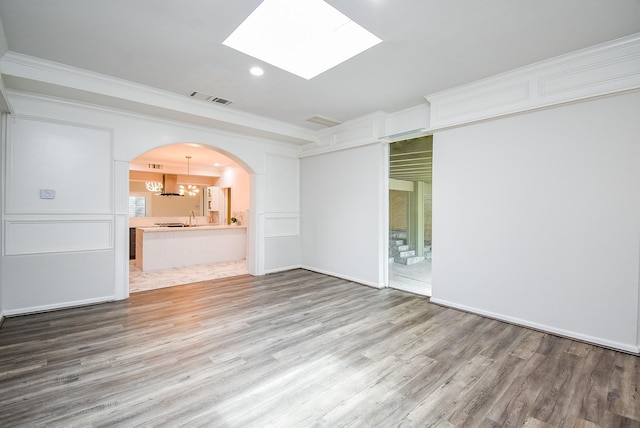 201 Vanderpool Ln Unit 27, Houston, TX 77024 - unfurnished living room featuring wood finished floors, ornamental molding, a skylight, recessed lighting, and arched walkways