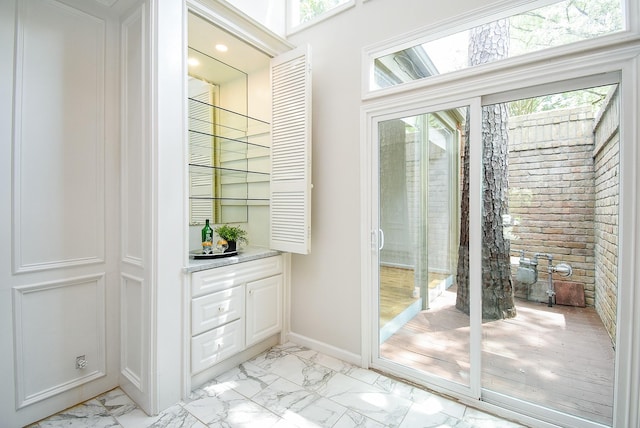 201 Vanderpool Ln Unit 27, Houston, TX 77024 - doorway to outside featuring light marble finish floors, baseboards, bar, and brick wall