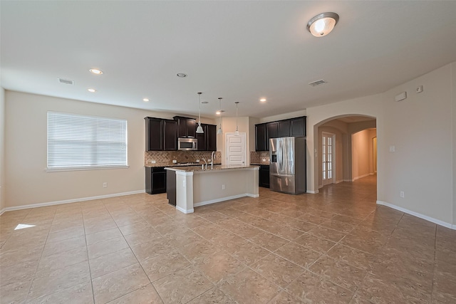 13513 Palo Lake Ln, Houston, TX 77044 - kitchen featuring appliances with stainless steel finishes, arched walkways, backsplash, a kitchen island with sink, and open floor plan