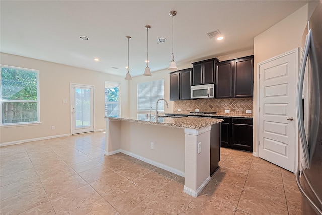 13513 Palo Lake Ln, Houston, TX 77044 - kitchen with appliances with stainless steel finishes, a sink, backsplash, light stone countertops, and a kitchen island with sink