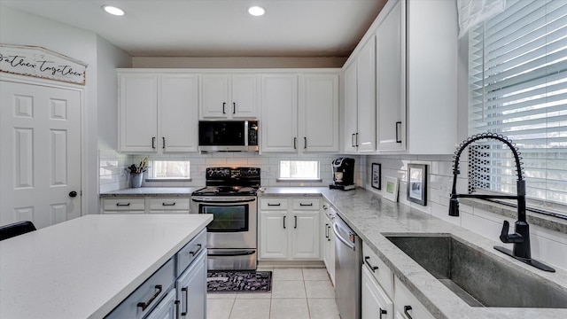 20703 Emerald Spruce Ct, Kingwood, TX 77346 - kitchen with appliances with stainless steel finishes, a sink, white cabinetry, decorative backsplash, and recessed lighting