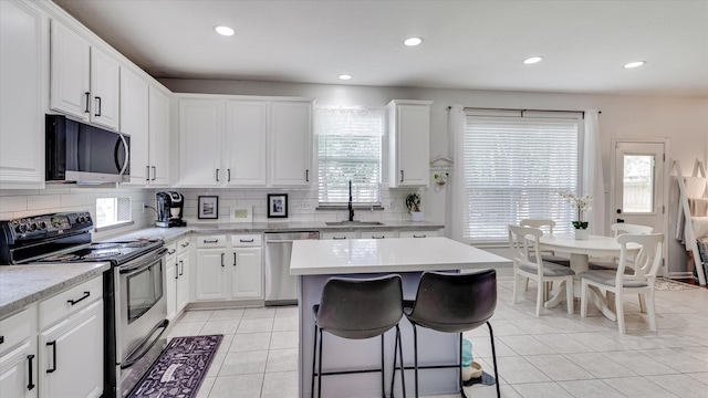 20703 Emerald Spruce Ct, Kingwood, TX 77346 - kitchen featuring stainless steel appliances, a sink, light tile patterned flooring, backsplash, and recessed lighting