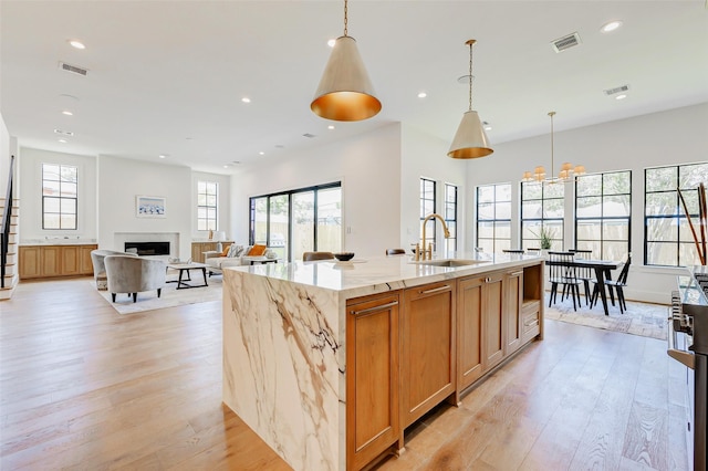 1810 Woodcrest Dr, Houston, TX 77018 - kitchen featuring a sink, light wood-style flooring, a fireplace, light stone counters, and recessed lighting