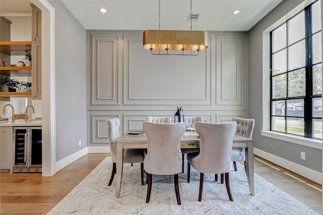 1810 Woodcrest Dr, Houston, TX 77018 - dining space featuring wine cooler, baseboards, light wood finished floors, a chandelier, and recessed lighting