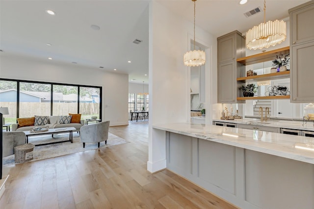 1810 Woodcrest Dr, Houston, TX 77018 - kitchen with a sink, light stone countertops, a chandelier, light wood-style flooring, and pendant lighting