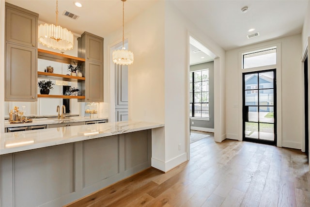 1810 Woodcrest Dr, Houston, TX 77018 - kitchen featuring light wood-style floors, a sink, baseboards, decorative light fixtures, and light stone counters