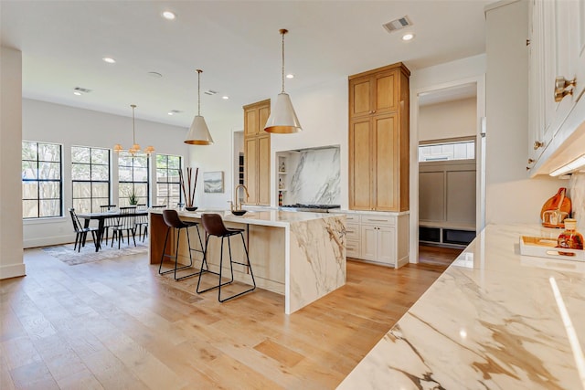 1810 Woodcrest Dr, Houston, TX 77018 - kitchen featuring healthy amount of natural light, a center island with sink, light wood-style floors, recessed lighting, and light stone counters