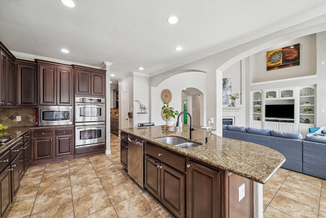 15718 Starcreek Ln, Houston, TX 77044 - kitchen featuring a sink, stainless steel appliances, ornamental molding, arched walkways, and a kitchen island with sink