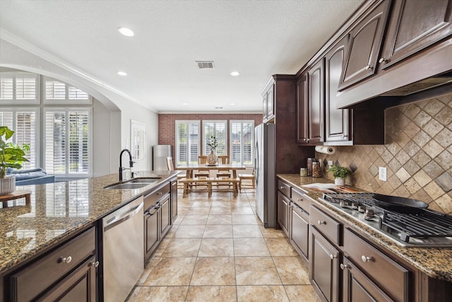 15718 Starcreek Ln, Houston, TX 77044 - kitchen featuring appliances with stainless steel finishes, a sink, dark brown cabinets, tasteful backsplash, and dark stone countertops