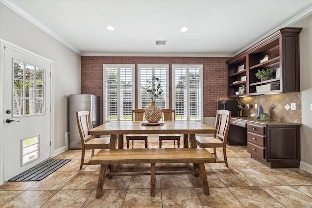 15718 Starcreek Ln, Houston, TX 77044 - dining area featuring ornamental molding, healthy amount of natural light, baseboards, brick wall, and light stone finish flooring