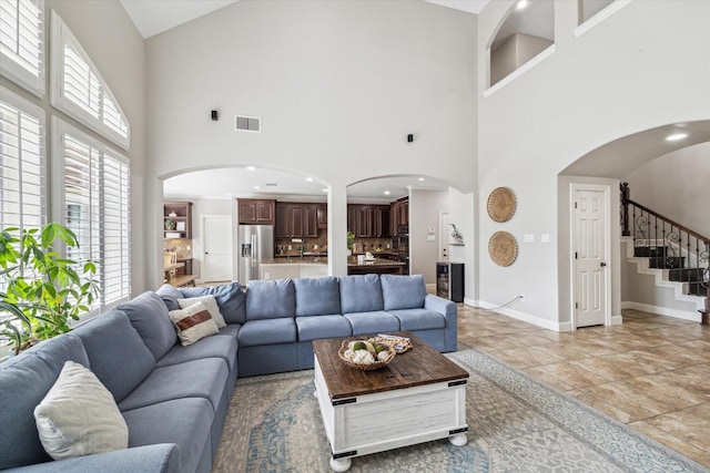 15718 Starcreek Ln, Houston, TX 77044 - living area with arched walkways, a high ceiling, stairway, baseboards, and recessed lighting