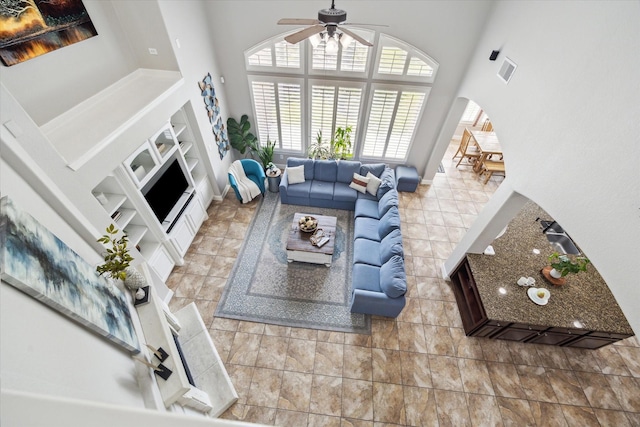 15718 Starcreek Ln, Houston, TX 77044 - living room featuring a ceiling fan, a towering ceiling, arched walkways, and baseboards