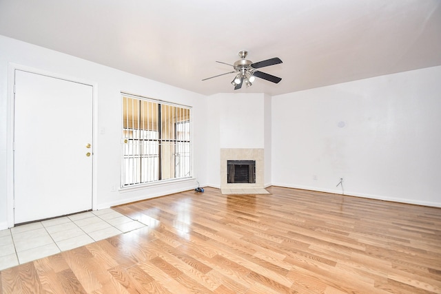 10100 S Gessner Rd Unit 308, Houston, TX 77071 - unfurnished living room with a ceiling fan, light wood-style flooring, a tile fireplace, and baseboards