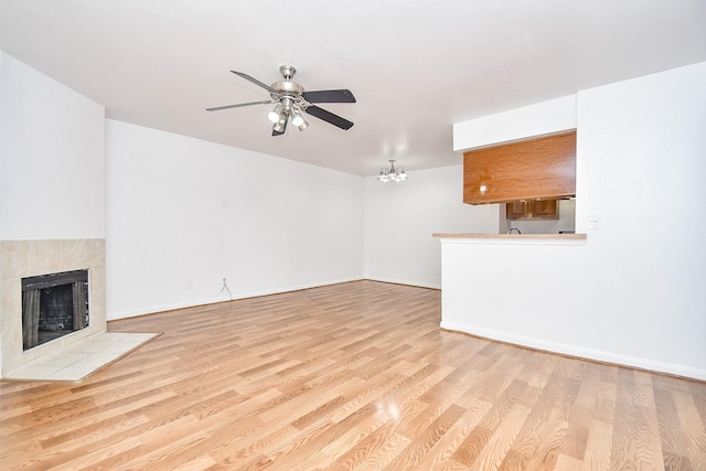 10100 S Gessner Rd Unit 308, Houston, TX 77071 - unfurnished living room with a ceiling fan, a tiled fireplace, wood finished floors, and baseboards
