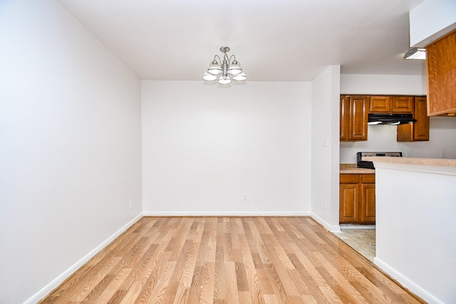10100 S Gessner Rd Unit 308, Houston, TX 77071 - kitchen with under cabinet range hood, brown cabinets, light wood finished floors, a chandelier, and light countertops