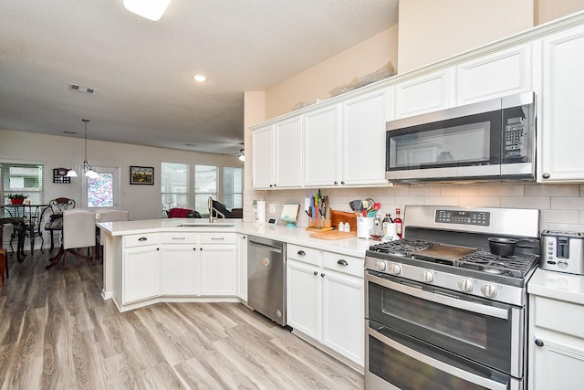 2206 Rocky Hollow Ln, Katy, TX 77450 - kitchen featuring appliances with stainless steel finishes, a sink, a peninsula, light wood-type flooring, and light countertops