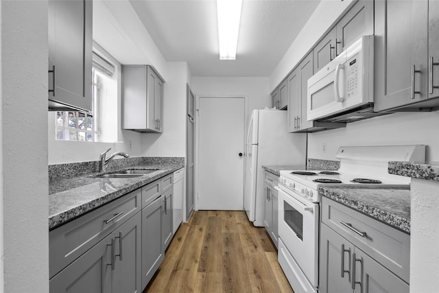 6500 Sands Point Dr Unit 107, Houston, TX 77074 - kitchen with white appliances, a sink, gray cabinetry, light wood-style flooring, and dark stone countertops