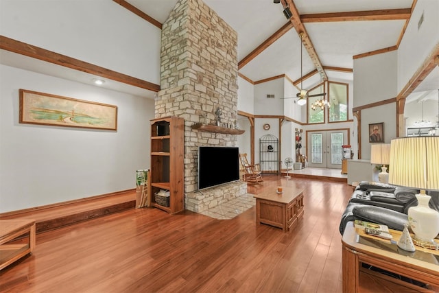 103 Whippoorwill Dr, Livingston, TX 77351 - living room with high vaulted ceiling, beamed ceiling, wood finished floors, a stone fireplace, and baseboards