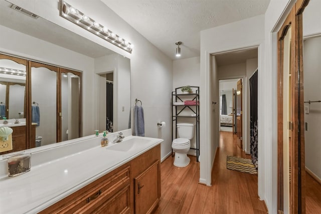 103 Whippoorwill Dr, Livingston, TX 77351 - bathroom featuring toilet, wood finished floors, vanity, baseboards, and a textured ceiling