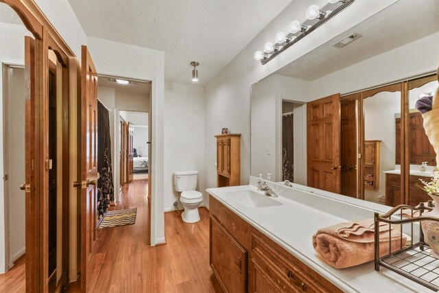 103 Whippoorwill Dr, Livingston, TX 77351 - full bath featuring wood finished floors, toilet, vanity, and a shower with shower curtain