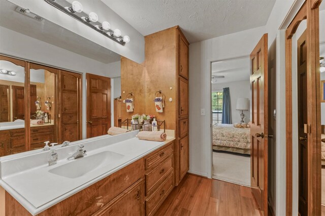 103 Whippoorwill Dr, Livingston, TX 77351 - ensuite bathroom with wood finished floors, vanity, and a textured ceiling