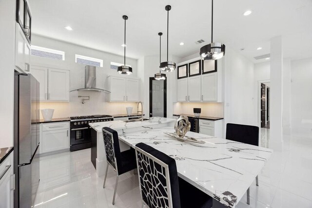 3379 Tampa St, Houston, TX 77021 - kitchen with wall chimney range hood, stainless steel appliances, a sink, a spacious island, and white cabinets