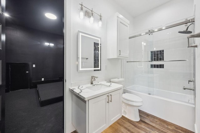 3379 Tampa St, Houston, TX 77021 - bathroom featuring toilet, vanity, enclosed tub / shower combo, and wood finished floors