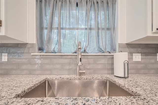 19426 Gladewater Dr, Tomball, TX 77375 - kitchen view of backsplash, a sink, white cabinetry, and light stone countertops