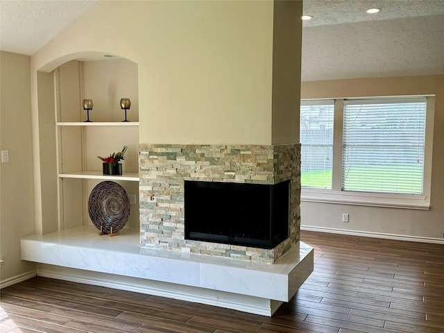 5035 Chappel Hill Dr, Missouri City, TX 77459 - detailed view of a textured ceiling, wood finished floors, a fireplace, baseboards, and arched walkways