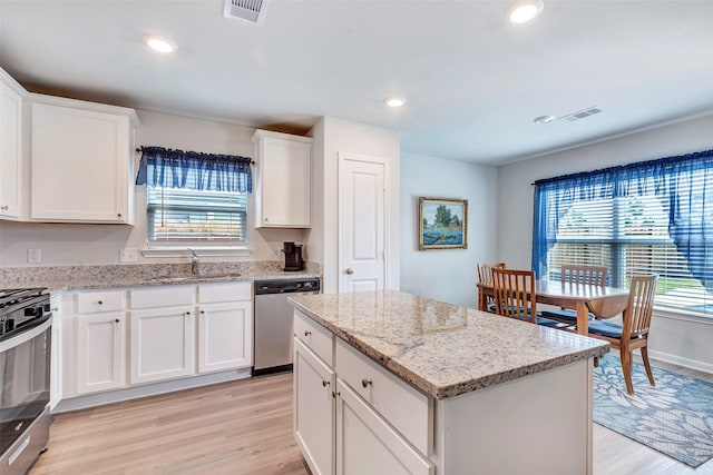 16134 Sugar Falls Dr, Conroe, TX 77303 - kitchen with stainless steel appliances, a sink, light wood-style flooring, white cabinetry, and a kitchen island