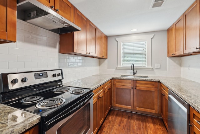 2604 Cochran St, Houston, TX 77009 - kitchen with appliances with stainless steel finishes, under cabinet range hood, a sink, dark wood-style floors, and brown cabinetry