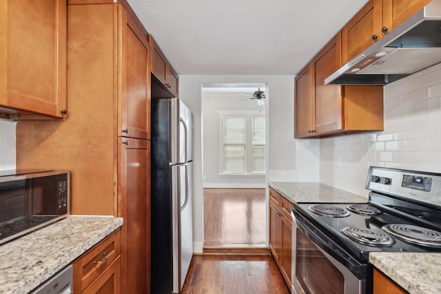 2604 Cochran St, Houston, TX 77009 - kitchen with appliances with stainless steel finishes, wall chimney range hood, dark wood-style floors, tasteful backsplash, and brown cabinetry