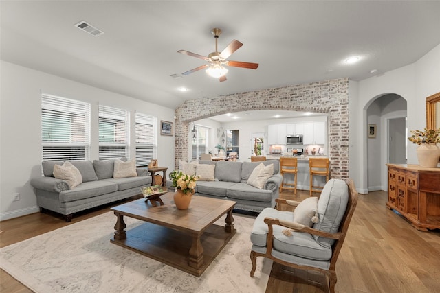 18731 Pilot Knolls Dr, Cypress, TX 77433 - living room featuring arched walkways, light wood-style flooring, a ceiling fan, baseboards, and healthy amount of natural light