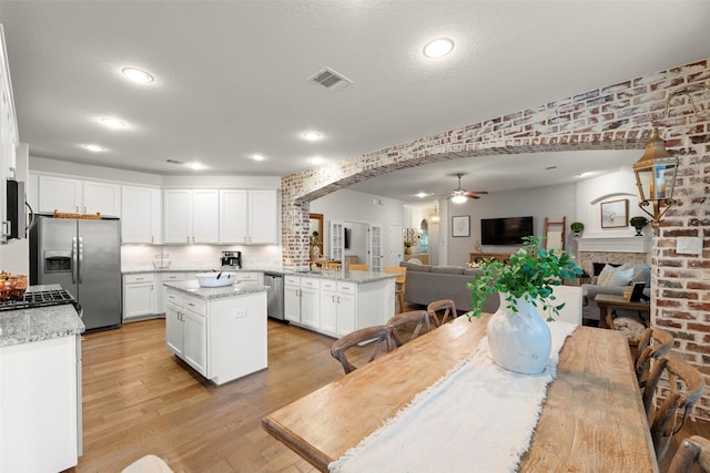18731 Pilot Knolls Dr, Cypress, TX 77433 - dining area featuring a ceiling fan, light wood-style flooring, arched walkways, a fireplace, and recessed lighting