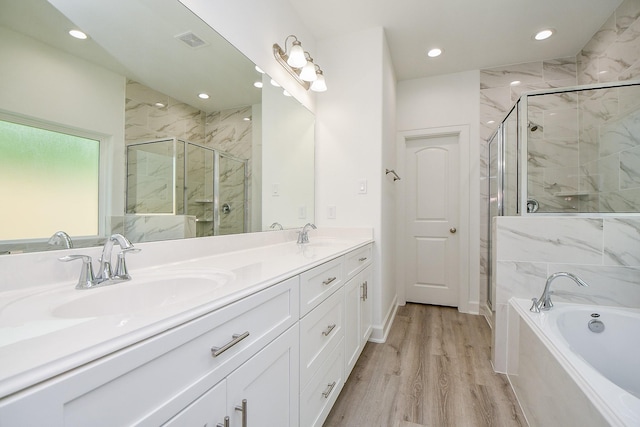 6727 Utah St, Houston, TX 77091 - bathroom with double vanity, a garden tub, a marble finish shower, wood finished floors, and recessed lighting