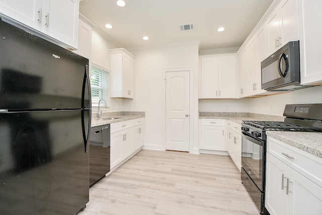 6727 Utah St, Houston, TX 77091 - kitchen with black appliances, a sink, white cabinetry, light wood-type flooring, and light stone counters