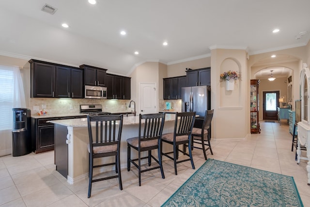 17915 Tall Chestnut St, Cypress, TX 77429 - kitchen featuring appliances with stainless steel finishes, arched walkways, tasteful backsplash, light stone counters, and ornamental molding