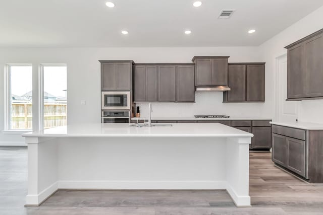 21118 Chelton Beach Dr, Cypress, TX 77433 - kitchen featuring stainless steel appliances, a sink, a kitchen island with sink, light countertops, and recessed lighting