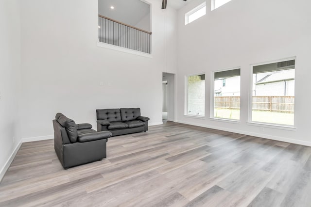 21118 Chelton Beach Dr, Cypress, TX 77433 - unfurnished living room with a towering ceiling, wood finished floors, a ceiling fan, and baseboards