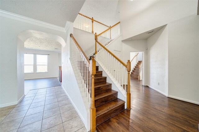 6610 Autumn Sunset Ln, Spring, TX 77379 - staircase with arched walkways, a textured ceiling, baseboards, crown molding, and wood finished floors