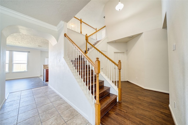 6610 Autumn Sunset Ln, Spring, TX 77379 - stairway with arched walkways, a textured ceiling, ornamental molding, baseboards, and wood finished floors