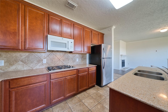6610 Autumn Sunset Ln, Spring, TX 77379 - kitchen with stainless steel appliances, a sink, backsplash, light tile patterned floors, and a textured ceiling