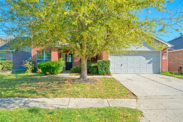 6610 Autumn Sunset Ln, Spring, TX 77379 - view of property hidden behind natural elements featuring brick siding, an attached garage, and driveway