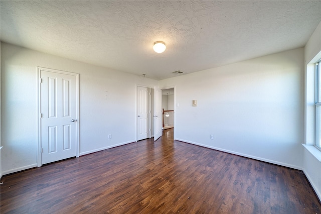 6610 Autumn Sunset Ln, Spring, TX 77379 - unfurnished bedroom featuring dark wood-style flooring, baseboards, two closets, and a textured ceiling