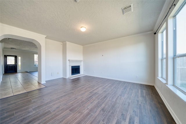 6610 Autumn Sunset Ln, Spring, TX 77379 - unfurnished living room with dark wood finished floors, a textured ceiling, arched walkways, baseboards, and ornamental molding