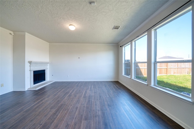 6610 Autumn Sunset Ln, Spring, TX 77379 - unfurnished living room featuring dark wood-style floors, a textured ceiling, baseboards, a fireplace with raised hearth, and crown molding