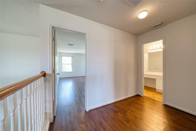 6610 Autumn Sunset Ln, Spring, TX 77379 - hallway featuring dark wood-style floors, a textured ceiling, baseboards, and an upstairs landing