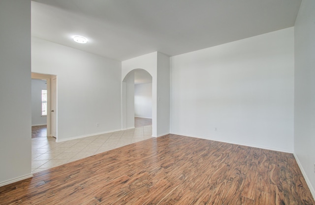 12223 Ayrshire Pl, Houston, TX 77089 - empty room featuring arched walkways, light wood-style floors, and baseboards