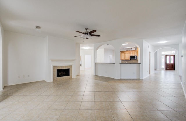 12223 Ayrshire Pl, Houston, TX 77089 - unfurnished living room featuring light tile patterned floors, ceiling fan, a fireplace, baseboards, and arched walkways